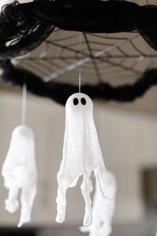 two ghosts made of cheesecloth hanging from spider web decoration