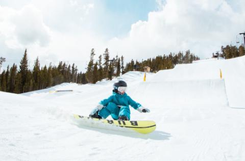 person in a green jacket snowboarding on a sunny day