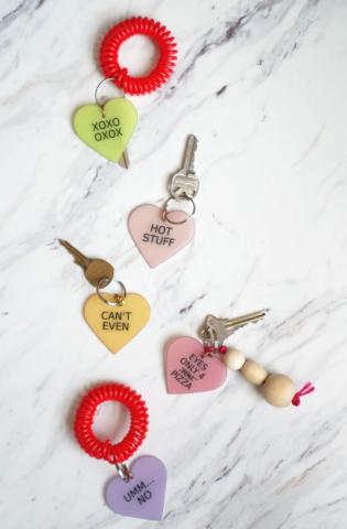 five pastel hearts with various valentines sayings on them attached to keys