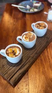 three small mugs of hot chocolate on a board for a tasting flight