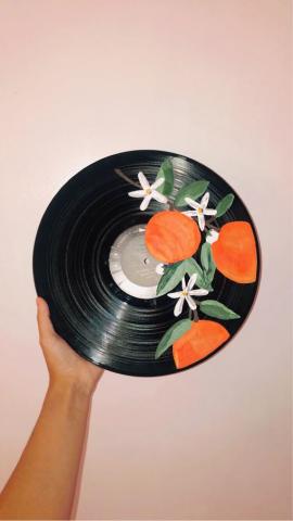 Hand holding vinyl record that has oranges painted on it