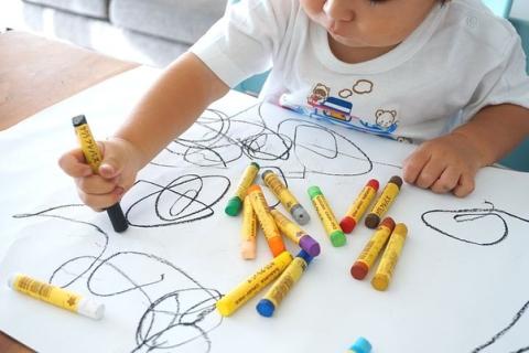 Young child drawing scribbles on a large piece of paper