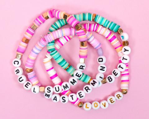a stack of beaded friendship bracelets with names of taylor swift songs 