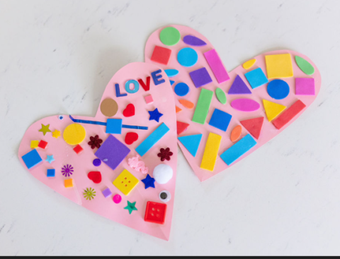 two paper hearts covered in various art supplies like buttons and stickers