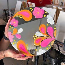 photo of round mirror painted with pink, orange and white in floral paisley design