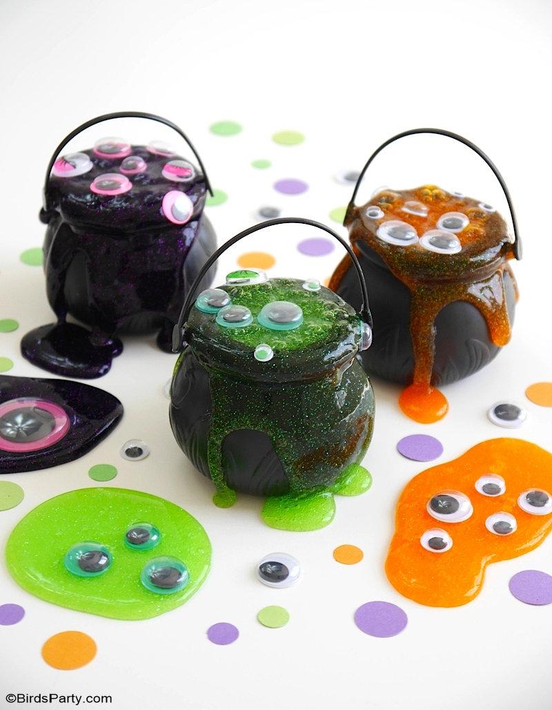 three small plastic cauldrons overflowing with glittery purple, green and orange slime topped with googly eyes